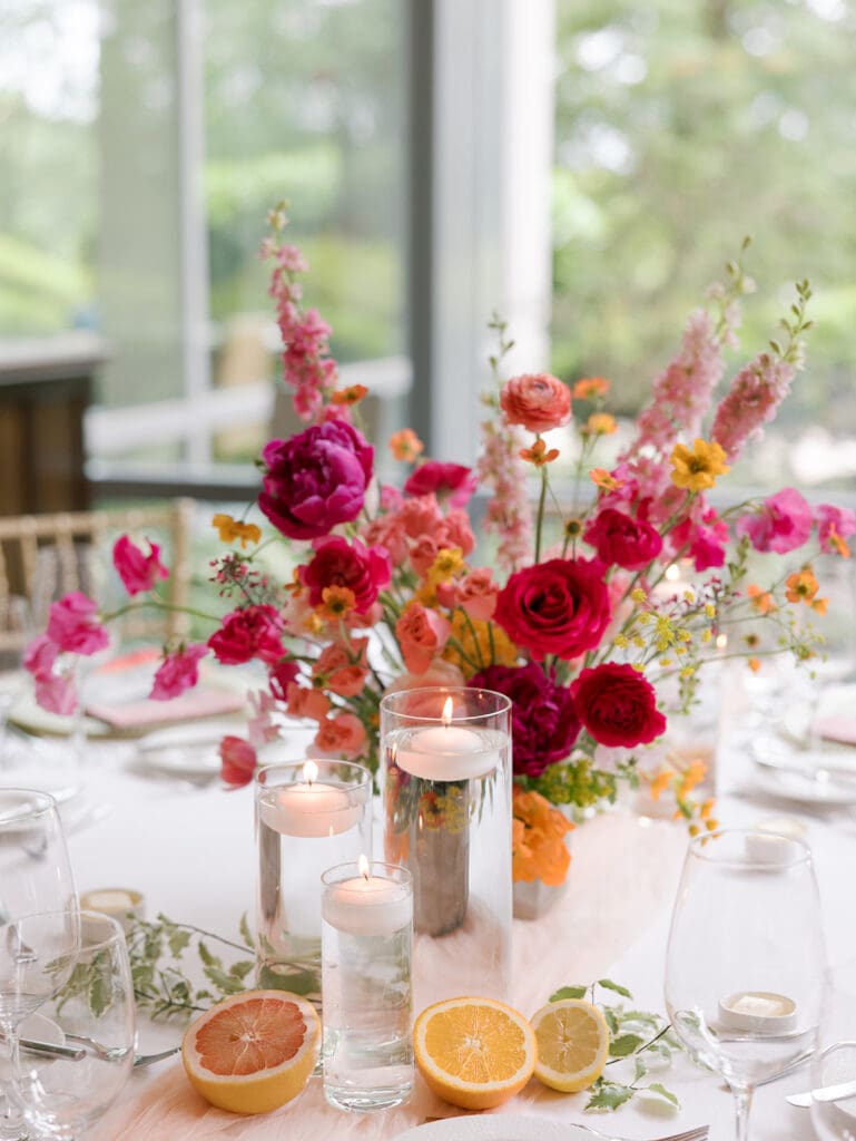 pink, orange, and yellow flower arrangement on wedding table scape in a well lit venue