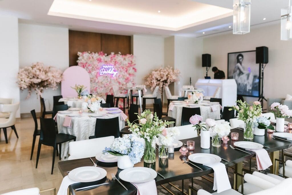 pastel floral themed party with pink floral back drops, black tables and chairs with organic pastel floral tablescape
