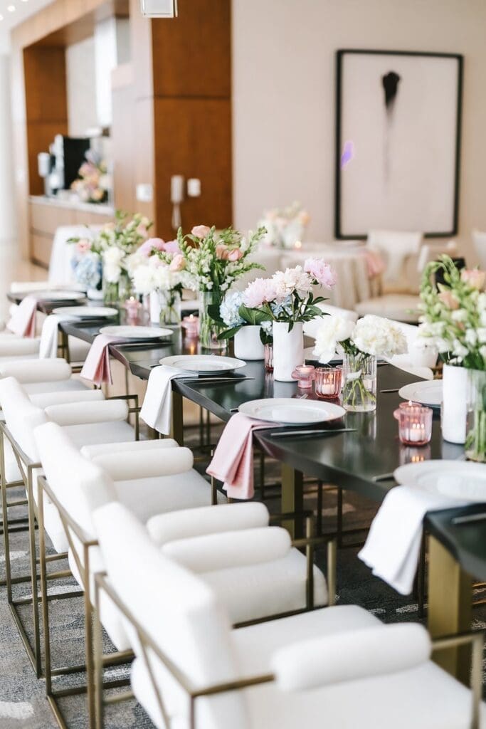 table scape of fresh pastel blooms with white chairs and pink linens