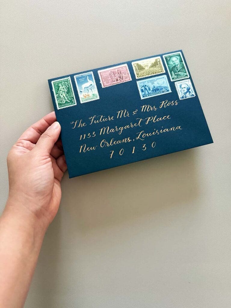 hand holding calligraphy on wedding invitation envelope, with vintage stamps and bronze ink 