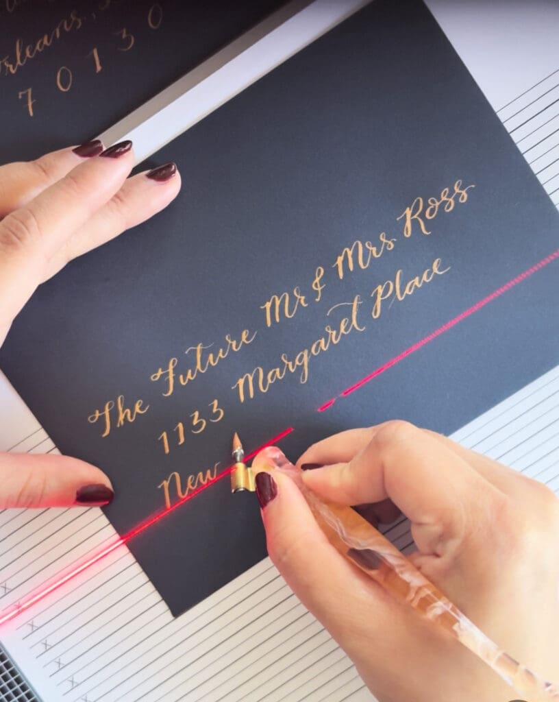 dc calligrapher writing guest addresses on navy envelope for wedding invitations using dip pen bronze ink